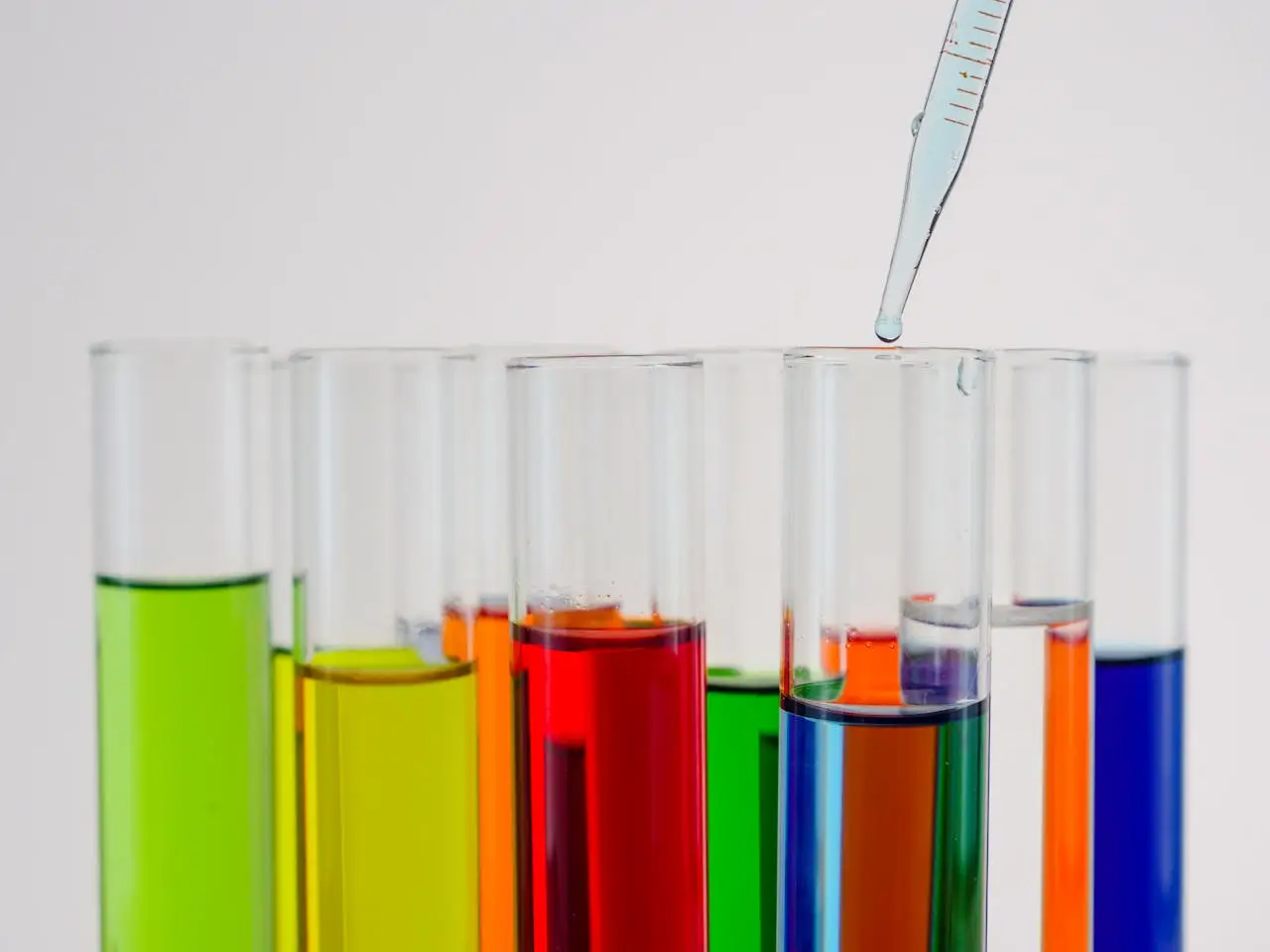services-01 Close-up of colorful liquid in test tubes with a dropping pipette in a laboratory setting.
